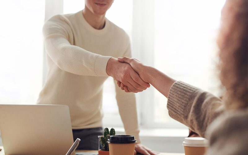 Sales representative shaking hands with a new customer across a desk